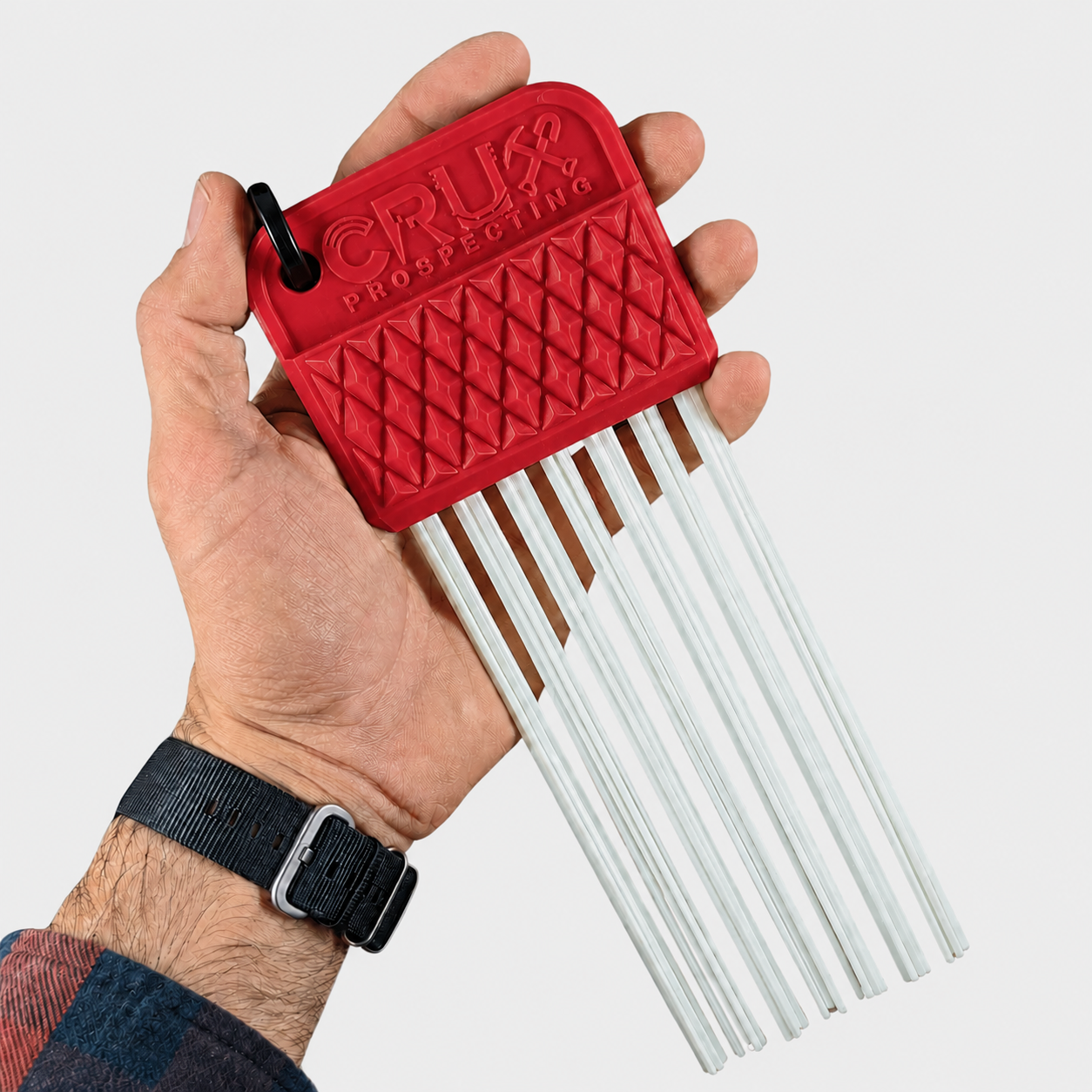 Red tool with white rods held by a hand on a light gray background